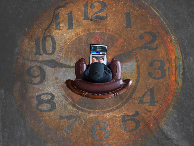 Developer with a laptop sitting on a chair inside of an analog clock on the ground